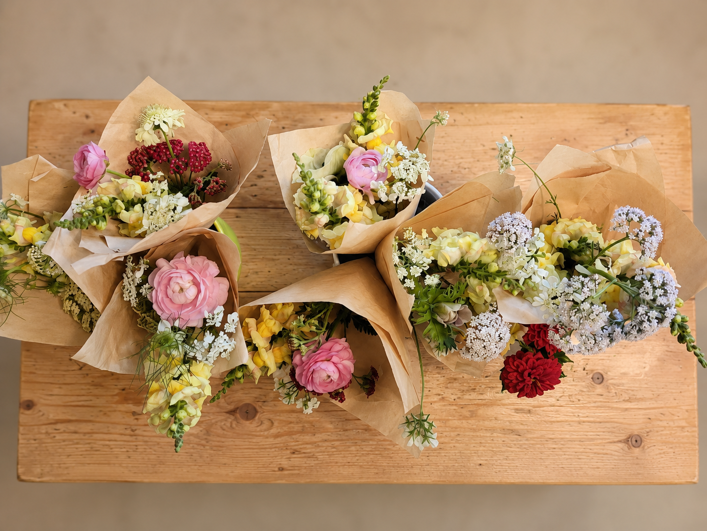 Paper-wrapped market bouquets on a wooden table